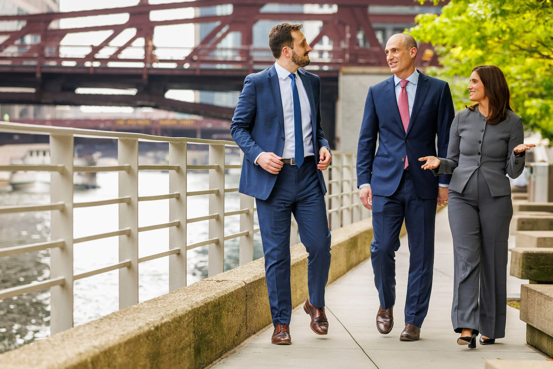 Two men and a woman in business attire, having a conversation while walking together.