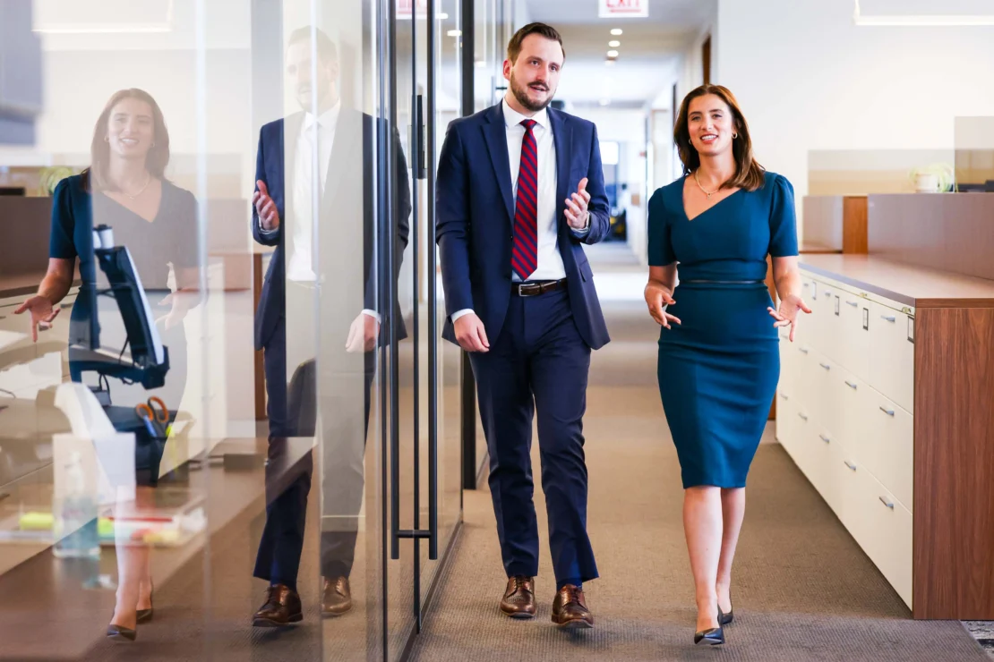 Dos abogados caminan por el pasillo de un despacho.